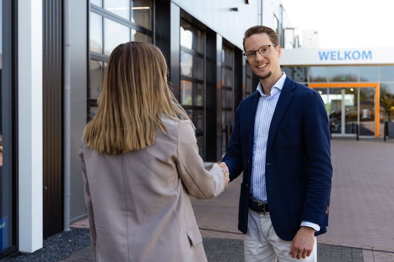 Twee mensen voor bedrijfsgebouw schudden hand